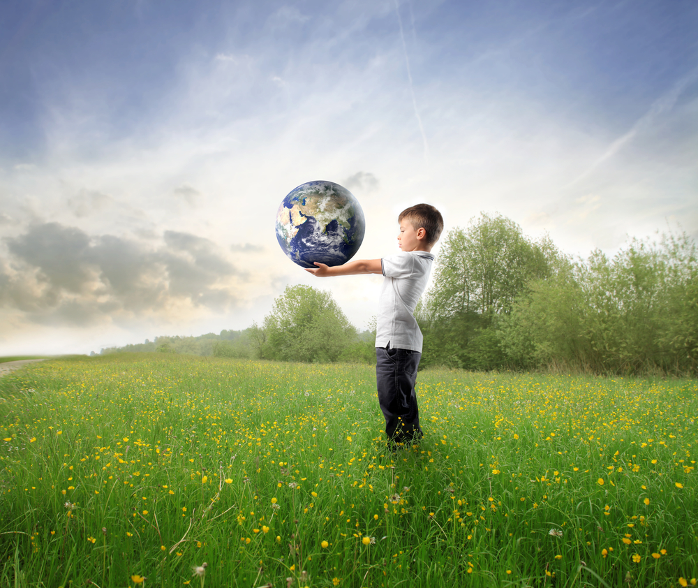 Niño en el campo con el planeta Tierra en sus manos
